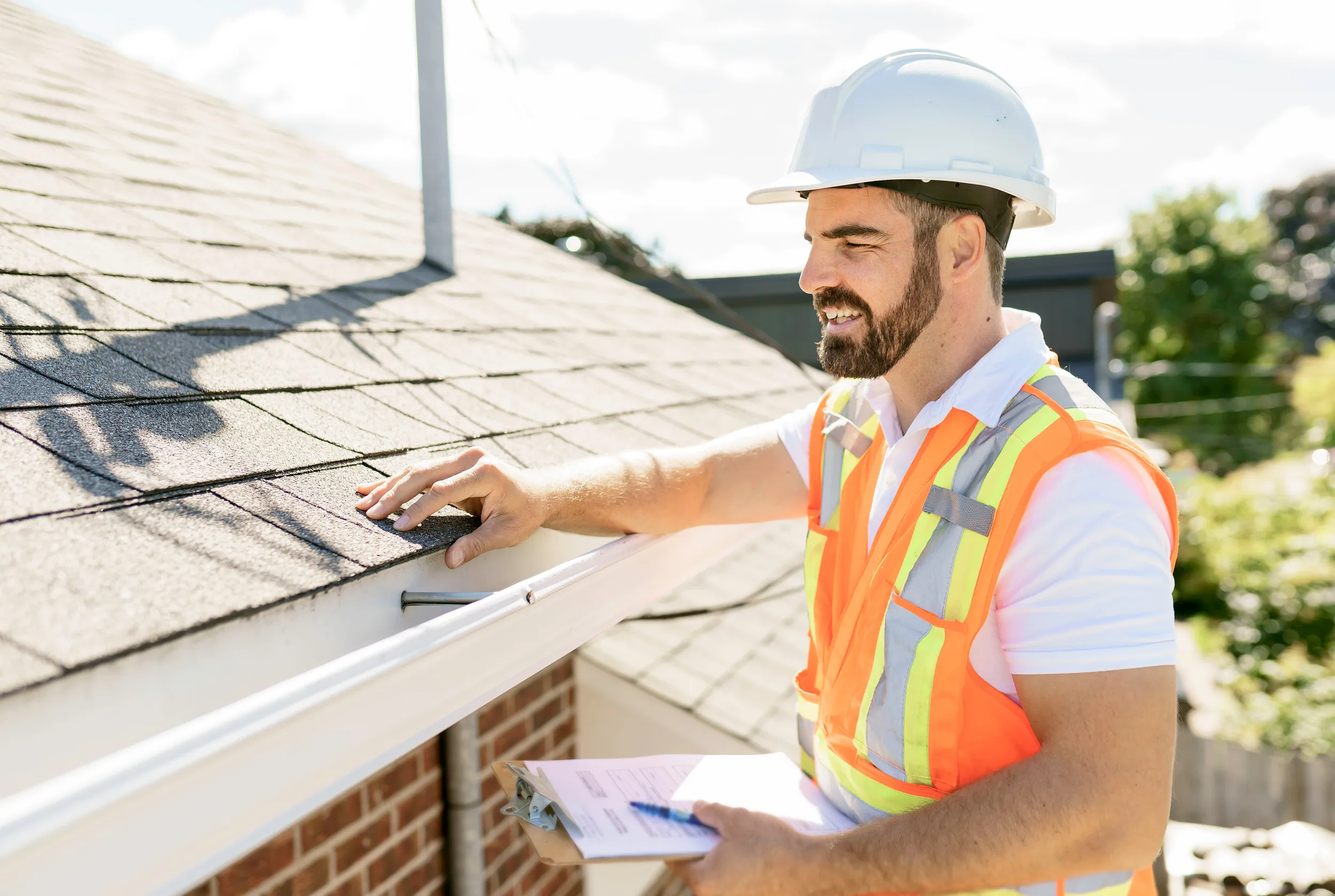 man in a hard hat, holding a clipboard, standing on the steps of an old rundown house